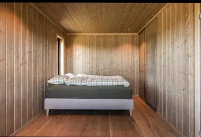 a bedroom with a bed in a wooden wall at New Cabin With Views Of Tisleiefjorden in Gol