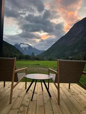 two chairs and a table on a deck with mountains at Nygård Panorama in Stryn