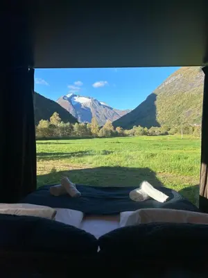 a bed with a view of a mountain through a window at Nygård Panorama in Stryn