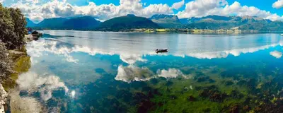 a boat on a lake with mountains in the background at Casa Hauge - Fjord View in Sandane