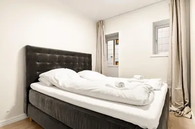 a bed with a black headboard and white sheets at Modern Apartment in Bergen