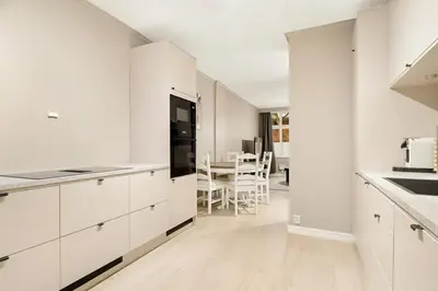 a white kitchen with white cabinets and a table at Modern Apartment in Bergen