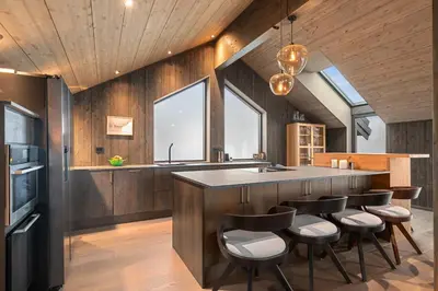 a kitchen with wooden walls and a island with bar stools at NEW cozy and large lodge with private Jacuzzi and sauna in Eggedal