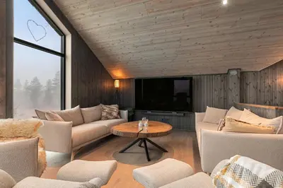 a living room with couches and a tv and a table at NEW cozy and large lodge with private Jacuzzi and sauna in Eggedal