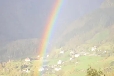 a rainbow over a valley with a town with at Utsikten in Masfjorden