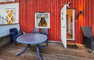 a table and chairs on a deck with a red wall at Amazing Apartment In Braskereidfoss With Wifi in Braskereidfoss