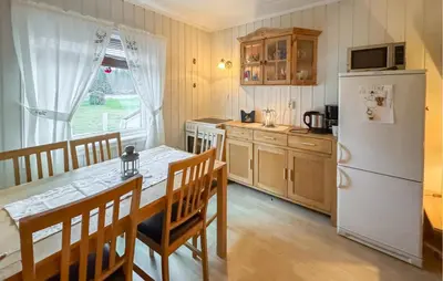 a kitchen with a table and a white refrigerator at Amazing Apartment In Braskereidfoss With Wifi in Braskereidfoss