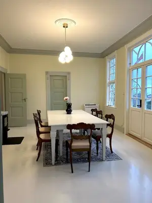 a dining room with a white table and chairs at Historic villa with large garden in Stord