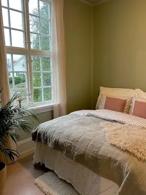 a bedroom with a bed and a large window at Historic villa with large garden in Stord