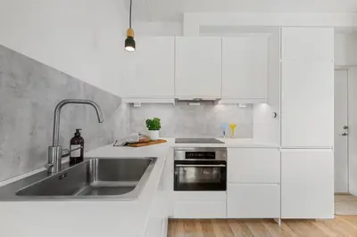 a kitchen with white cabinets and a stainless steel sink at Central 3-room apartment in Trondheim