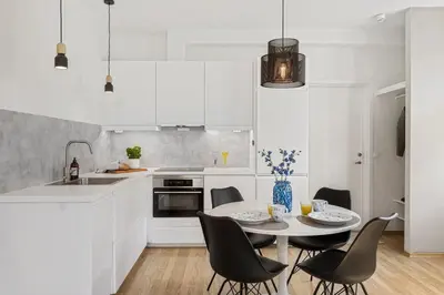 a kitchen with white cabinets and a table and chairs at Central 3-room apartment in Trondheim