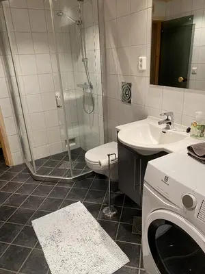 a bathroom with a shower and a toilet and a washing machine at Ski-in & ski-out apartment in Hafjell in Øyer