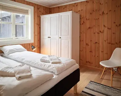a bedroom with two beds and a cabinet and a chair at Stranda Fjellgrend 2 bedrooms - 76B in Stranda