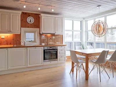 a kitchen with white cabinets and a table and chairs at Stranda Fjellgrend 2 bedrooms - 76B in Stranda