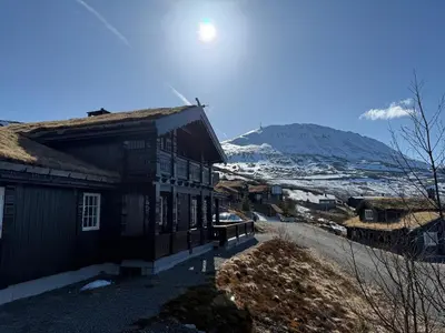 a wooden house with a mountain in the background at Rustik hytte i Gausta, ski in, ski out, 10 beds in Gaustablikk