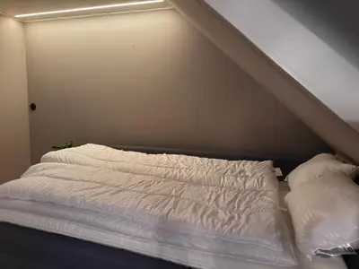 a bed with white sheets and pillows in a room at Cozy Apartment Next to Solsiden in Trondheim