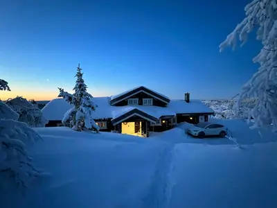 a house covered in snow with a car in front at Family Cabin With Panoramic Views In Aurdalsåsen in Aurdal