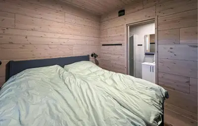 a bed in a room with a wooden wall at Amazing Apartment In Øyer With Wifi in Øyer