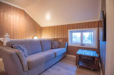 a living room with a blue couch and a window at Sentralen in Trysil