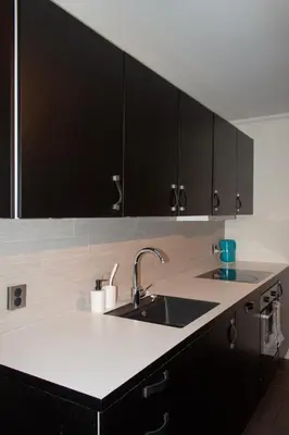 a kitchen with a sink and black cabinets at Cozy 2BD apartment in Central Bergen in Bergen