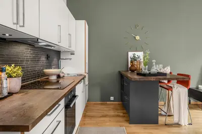 a kitchen with white cabinets and a clock on the wall at Midtbyen Apartment in Trondheim