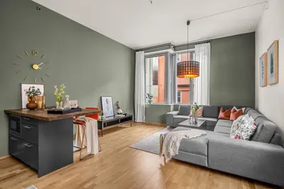 a living room with a couch and a clock on the wall at Midtbyen Apartment in Trondheim