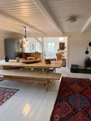 a living room with a table and a rug at Historic Timber Cabin With Views Of Rondane in Furuhovde