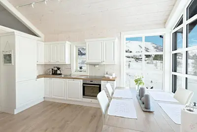 a kitchen with white cabinets and a table with chairs at Stranda Fjellgrend 2 bedrooms and loft - 16B in Stranda