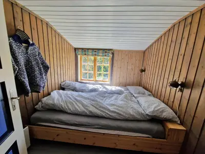 a bed in a wooden room with a window at Trivelig og romslig hytte nær Røros, rikelig med uteplass in Glåmos