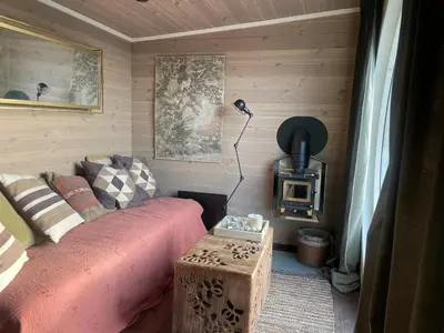 a living room with a couch and a wood stove at Tiny house on wheels with great views Sjusjøen in Mesnali