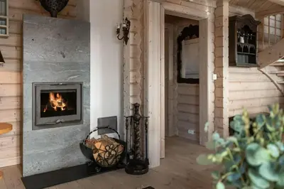 a fireplace in a living room with a wooden wall at Timber Cabin With Panoramic Views At Spåtind in Etnedal