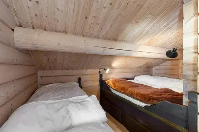 two beds in a room with wooden walls at Timber Cabin With Panoramic Views At Spåtind in Etnedal