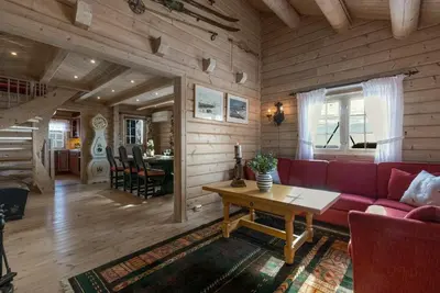 a living room with a red couch and a table at Timber Cabin With Panoramic Views At Spåtind in Etnedal