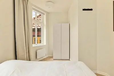 a white bedroom with a bed and a window at Modern 1BR in heart of old town in Bergen