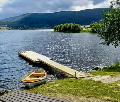 a boat is docked at a dock on a lake at Lake Resort - Pool & Sauna in Vossevangen