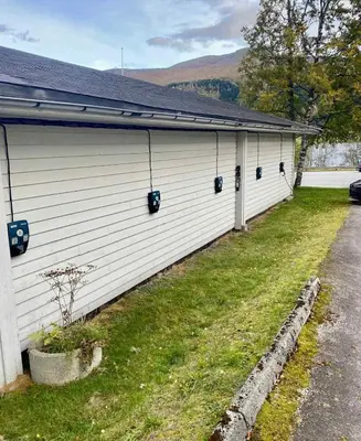 a white building with a yard next to a house at Lake Resort - Pool & Sauna in Vossevangen