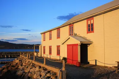 a building with a red door next to a body of water at Gunnabuda in Longva