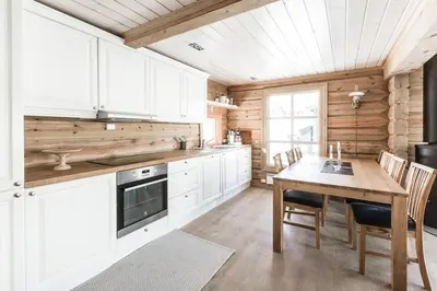 a kitchen with white cabinets and a wooden table at Stranda Fjellgrend 3 bedrooms - 68B in Stranda