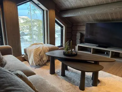 a living room with a table and a large screen tv at New exclusive cabin - panoramic view with ski in-out, Kvitfjell Varden in Ringebu