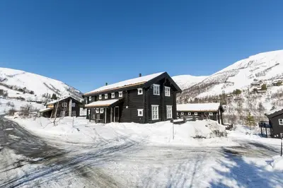 a large wooden house in the snow with mountains at Stranda Fjellgrend 3 bedrooms - 68A in Stranda
