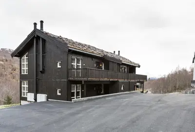 a black building with a balcony on the side of a road at Stranda Fjellgrend 3 bedrooms and loft - 80D in Stranda