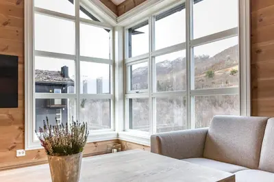 a living room with a table and large windows at Stranda Fjellgrend 3 bedrooms and loft - 80D in Stranda