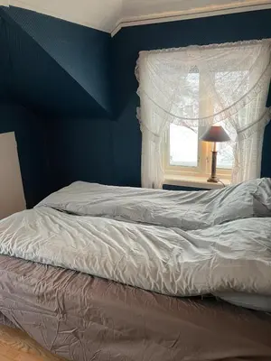 a bedroom with a bed with a blue wall and a window at Holiday home in Espevær in Bømlo
