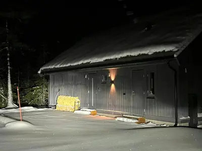 a barn with snow on the roof at night at Warm And Inviting Cabin Near Norefjell in Eggedal