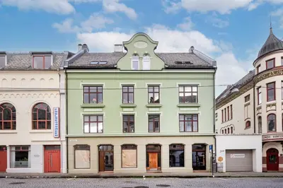a green building on a street next to other buildings at Art Nouveau in the middle of downtown Ålesund in Ålesund