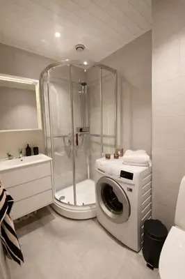 a bathroom with a shower and a washing machine at Art Nouveau in the middle of downtown Ålesund in Ålesund