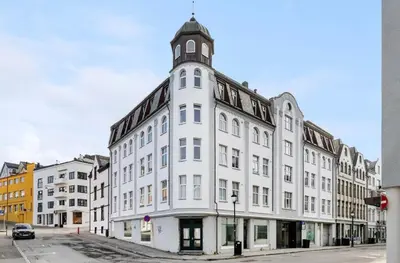 a white building with a clock tower on a street at Bright and modern city center apartment in Ålesund