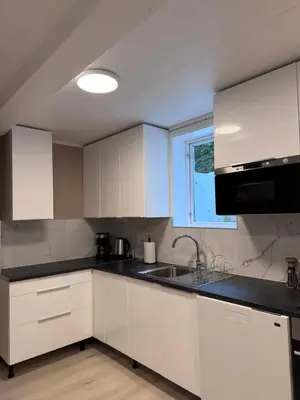 a kitchen with white cabinets and a sink and a window at Kirkevegen apartment in Brumunddalen