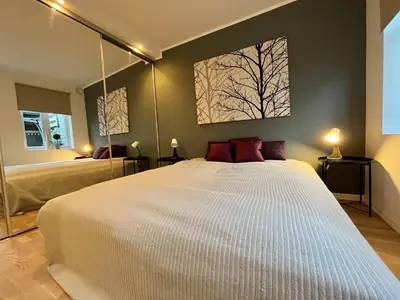 a bedroom with a white bed and a tree picture on the wall at Eksklusiv leilighet sentralt i Bergen in Bergen