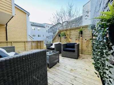 a patio with wicker furniture on a wooden deck at Eksklusiv leilighet sentralt i Bergen in Bergen